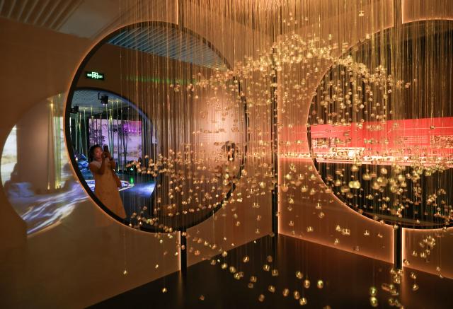 (260714) -- BEIJING, July 14, 2026 (Xinhua) -- A visitor takes photos during "A Garden Within: An Immersive Light and Shadow Exhibition of the Qianlong Garden" at National Museum of Classic Books in Beijing, capital of China, July 14, 2026. The exhibition, which features multiple immersive scenarios and interactive installations, is held here from July 9 to Dec. 6.
   The Qianlong Garden, also known as the Garden of the Palace of Tranquil Longevity, was built by Emperor Qianlong (1711-1799) of Qing Dynasty (1644-1911) as a private retreat for his later years in the Forbidden City, or today's Palace Museum. (Xinhua/Yin Gang)