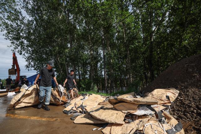 (260714) -- SHENYANG, July 14, 2026 (Xinhua) -- Emergency workers transfer supplies for prevention of floodwaters from overtopping a dike at Yujiatai Village of Liaozhong District, Shenyang, northeast China's Liaoning Province, July 14, 2026. Emergency responding workers in riverside towns and villages of Liaozhong District of Shenyang are working to heighten and reinforce the dikes as upstream flood discharge continues to rise the water level in the river. (Xinhua/Pan Yulong)