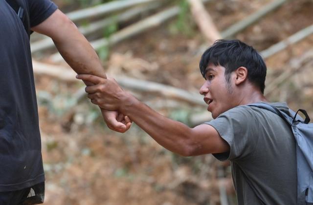(260714) -- NANNING, July 14, 2026 (Xinhua) -- A volunteer (R) helps people going through the landslide section of a road in Zhenlong Township, Hengzhou City, south China's Guangxi Zhuang Autonomous Region, July 10, 2026. Efforts are underway to support flood relief and recovery in Guangxi, which has been hit by severe rainstorms and flooding caused by Typhoon Maysak. (Xinhua/Huang Xiaobang)