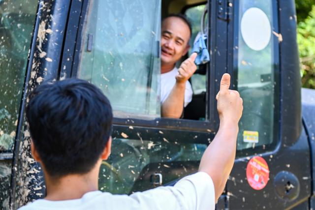 (260714) -- NANNING, July 14, 2026 (Xinhua) -- A villager (front) gestures to a rescuer in Naxu Village, Zhenlong Township, Hengzhou City, south China's Guangxi Zhuang Autonomous Region, July 13, 2026. Efforts are underway to support flood relief and recovery in Guangxi, which has been hit by severe rainstorms and flooding caused by Typhoon Maysak. (Xinhua/Cao Yiming)
