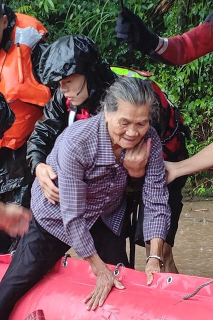 (260714) -- NANNING, July 14, 2026 (Xinhua) -- A rescuer helps a trapped villager to prepare for relocation in Jiulong Town, Qinzhou City, south China's Guangxi Zhuang Autonomous Region, July 6, 2026. Efforts are underway to support flood relief and recovery in Guangxi, which has been hit by severe rainstorms and flooding caused by Typhoon Maysak. (Xinhua/Zhang Ailin)