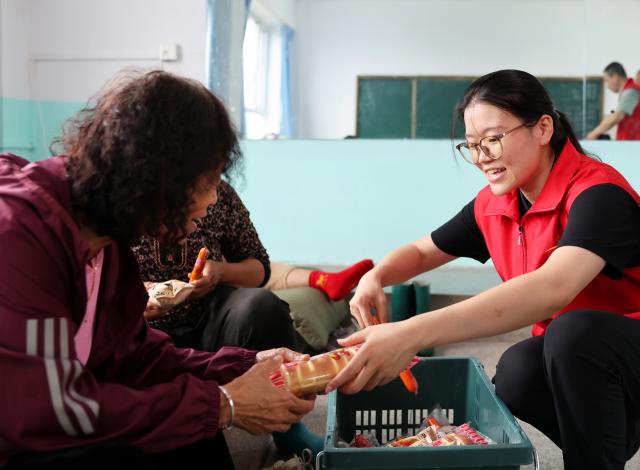 (260714) -- BEIJING, July 14, 2026 (Xinhua) -- A staff member (R) delivers food to evacuated people at a temporary relocation in Kaiyuan, Tieling, northeast China's Liaoning Province, July 14, 2026. Torrential rain has caused flooding in multiple places in China recently. In rescue across the country, rescuers have risen to the occasion to protect the people. (Xinhua/Han He)