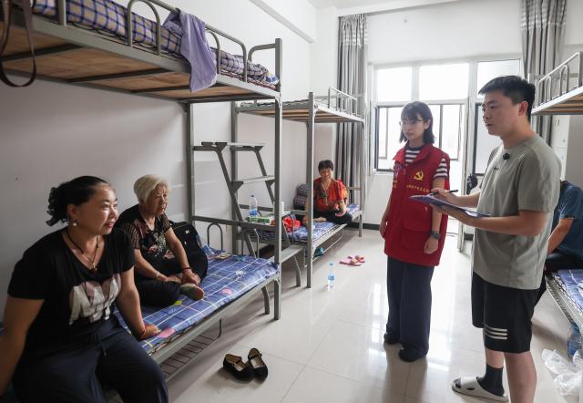 (260714) -- BEIJING, July 14, 2026 (Xinhua) -- Staff members talk with evacuated people at a temporary relocation in Shenyang, northeast China's Liaoning Province, July 14, 2026. Torrential rain has caused flooding in multiple places in China recently. In rescue across the country, rescuers have risen to the occasion to protect the people. (Xinhua/Pan Yulong)