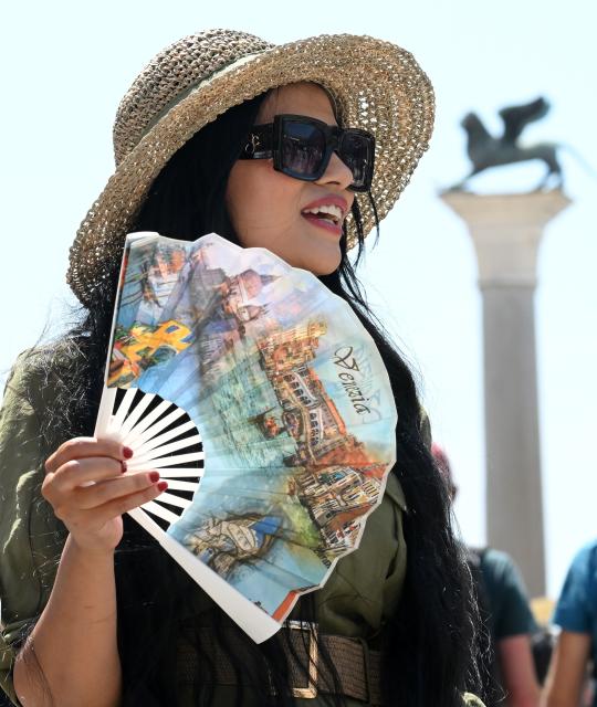 (260714) -- VENICE, July 14, 2026 (Xinhua) -- A tourist uses a folding fan to cool off at San Marco Square in Venice, Italy, on July 14, 2026. (Photo by Alberto Lingria/Xinhua)