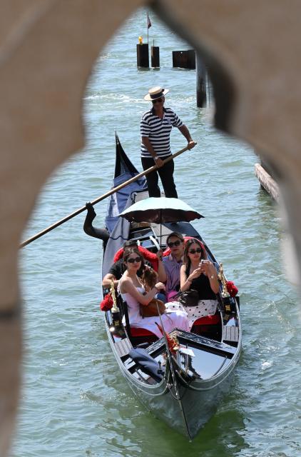 (260714) -- VENICE, July 14, 2026 (Xinhua) -- Tourists shield themselves from the sun with a parasol on a gondola in Venice, Italy, on July 14, 2026. (Photo by Alberto Lingria/Xinhua)