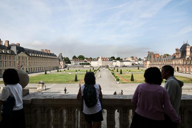 (260715) -- BEIJING, July 15, 2026 (Xinhua) -- Tourists visit the Palace of Fontainebleau in Seine-et-Marne, France, as smoke from a wildfire is seen in the distance, on July 14, 2026. French police have detained 59 people across the country in connection with wildfires, including two suspects linked to the blaze in the Fontainebleau forest in Seine-et-Marne department, southeast of Paris, French Interior Minister Laurent Nunez said on Monday.
   The wildfire in the Fontainebleau forest broke out on Sunday evening and continued to spread on Monday. (Xinhua/Wu Huiwo)
