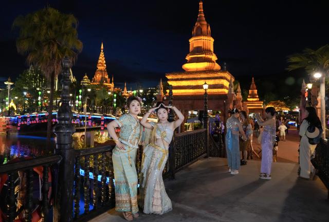 (260715) -- XISHUANGBANNA, July 15, 2026 (Xinhua) -- Tourists in ethnic attire pose for photos at the Starlight Night Market in Jinghong, Xishuangbanna Dai Autonomous Prefecture, southwest China's Yunnan Province, July 14, 2026. The Starlight Night Market, located in Jinghong of Xishuangbanna Dai Autonomous Prefecture, has witnessed a surge in visitor arrivals during the summer peak tourism season. Featuring local delicacies, ethnic culture and diverse nighttime consumption options, this night market reflects the vitality of local cultural and tourism market. (Xinhua/Chen Xinbo)