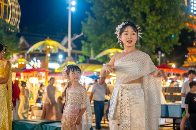(260715) -- XISHUANGBANNA, July 15, 2026 (Xinhua) -- Tourists in ethnic attire are seen at the Starlight Night Market in Jinghong, Xishuangbanna Dai Autonomous Prefecture, southwest China's Yunnan Province, July 14, 2026. The Starlight Night Market, located in Jinghong of Xishuangbanna Dai Autonomous Prefecture, has witnessed a surge in visitor arrivals during the summer peak tourism season. Featuring local delicacies, ethnic culture and diverse nighttime consumption options, this night market reflects the vitality of local cultural and tourism market. (Photo by Ren Jun/Xinhua)