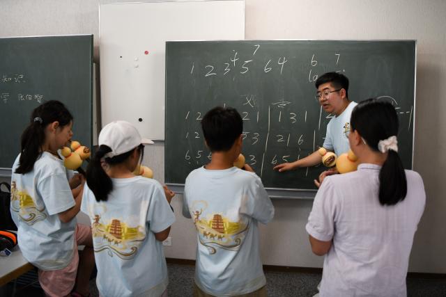 (260715) -- BERN, July 15, 2026 (Xinhua) -- Members of a Chinese culture summer camp learn to play the Hulusi, a traditional Chinese wind instrument, in Bern, Switzerland, July 14, 2026. A summer camp featuring traditional Chinese culture opened here on Tuesday. (Xinhua/Lian Yi)