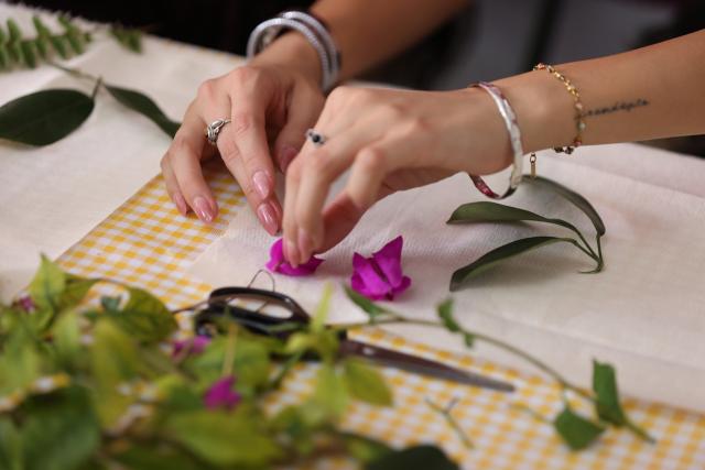 (260715) -- MEXICO CITY, July 15, 2026 (Xinhua) -- A visitor experiences eco-printing with petals and fresh-cut leaves at the San Angel Flower Fair in Mexico City, Mexico, July 14, 2026. The annual event features flower markets, handicraft displays and cultural performances, highlighting local horticulture traditions, folk art and the historic charm of the district. (Xinhua/Liu Wenhui)