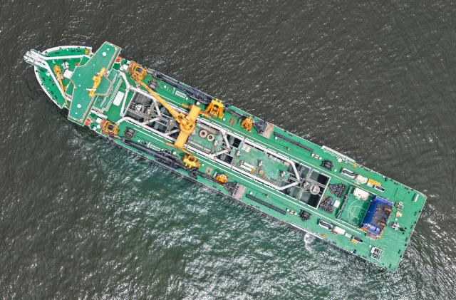(260715) -- GUANGZHOU, July 15, 2026 (Xinhua) -- An aerial drone photo taken on July 14, 2026 shows the "Junguang" dredger at the Beibu Gulf in south China's Guangxi Zhuang Autonomous Region. The "Junguang," a mega dredger with a 35,000 cubic meter capacity, was recently put into operation. Measuring 198 meters in length, with a maximum dredging depth of 120 meters and a deadweight of 60,483 tonnes, the vessel is the largest of its kind in Asia. 
  The vessel is equipped with the self-developed intelligent dredging control systems. It is capable of exceptional performance, including strong soil penetration, deep dredging, long-distance transport, and extended blowing capabilities. It is expected to be widely used in port and waterway dredging, deep-sea sand extraction, land reclamation, deep-sea mining, trench excavation and backfilling, gravel bed construction, and deep-sea pipeline laying. (Xinhua/Deng Hua)
