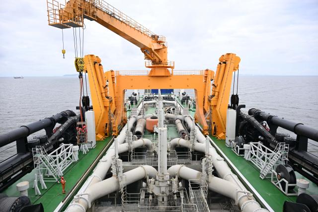 (260715) -- GUANGZHOU, July 15, 2026 (Xinhua) -- Staff members work on the deck of the "Junguang" dredger on July 14, 2026. The "Junguang," a mega dredger with a 35,000 cubic meter capacity, was recently put into operation. Measuring 198 meters in length, with a maximum dredging depth of 120 meters and a deadweight of 60,483 tonnes, the vessel is the largest of its kind in Asia. 
  The vessel is equipped with the self-developed intelligent dredging control systems. It is capable of exceptional performance, including strong soil penetration, deep dredging, long-distance transport, and extended blowing capabilities. It is expected to be widely used in port and waterway dredging, deep-sea sand extraction, land reclamation, deep-sea mining, trench excavation and backfilling, gravel bed construction, and deep-sea pipeline laying. (Xinhua/Deng Hua)