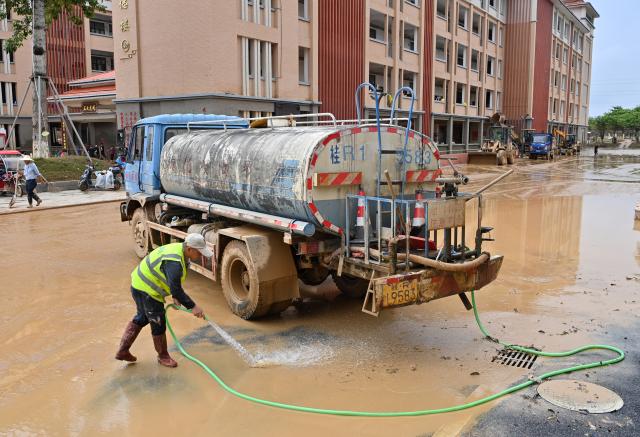(260715) -- GUIGANG, July 15, 2026 (Xinhua) -- People clear mud after flooding at a high school in Guigang, south China's Guangxi Zhuang Autonomous Region, July 15, 2026. Flood relief and recovery efforts were underway after the city was hit by severe rainstorms and flooding caused by Typhoon Maysak. (Xinhua/Lu Boan)
