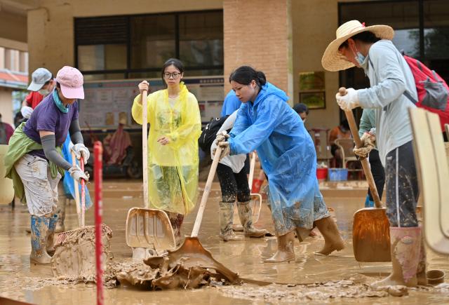 (260715) -- GUIGANG, July 15, 2026 (Xinhua) -- People clear mud after flooding at a high school in Guigang, south China's Guangxi Zhuang Autonomous Region, July 15, 2026. Flood relief and recovery efforts were underway after the city was hit by severe rainstorms and flooding caused by Typhoon Maysak. (Xinhua/Lu Boan)