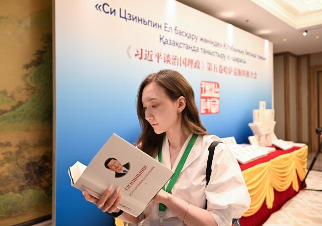 (260715) -- ASTANA, July 15, 2026 (Xinhua) -- A journalist reads a copy of "Xi Jinping: The Governance of China" at an event promoting the fifth volume of the book in Astana, Kazakhstan, July 15, 2026. The event was held here on Wednesday. (Xinhua/Li Renzi)