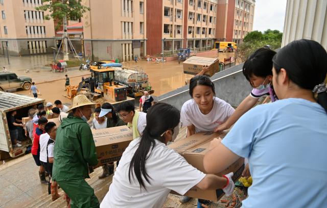 (260715) -- NANNING, July 15, 2026 (Xinhua) -- People transfer disaster relief supplies at a middle school in Guigang City, south China's Guangxi Zhuang Autonomous Region, July 15, 2026. Efforts are underway to facilitate flood relief and recovery in Guangxi, which has been hit by severe rainstorms and flooding caused by Typhoon Maysak. (Xinhua/Lu Boan)
