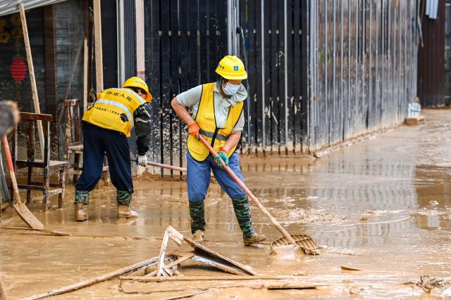 (260715) -- NANNING, July 15, 2026 (Xinhua) -- Staff members remove sludge in Yunbiao Town of Hengzhou City, Nanning City of south China's Guangxi Zhuang Autonomous Region, July 14, 2026. Efforts are underway to facilitate flood relief and recovery in Guangxi, which has been hit by severe rainstorms and flooding caused by Typhoon Maysak. (Xinhua/Cao Yiming)