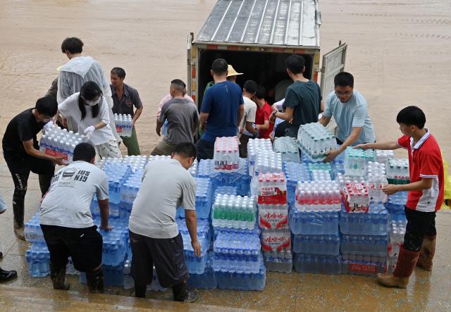 (260715) -- NANNING, July 15, 2026 (Xinhua) -- People transfer disaster relief supplies at a middle school in Guigang City, south China's Guangxi Zhuang Autonomous Region, July 15, 2026. Efforts are underway to facilitate flood relief and recovery in Guangxi, which has been hit by severe rainstorms and flooding caused by Typhoon Maysak. (Xinhua/Lu Boan)