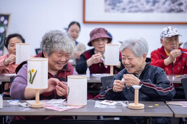 (260715) -- BEIJING, July 15, 2026 (Xinhua) -- Seniors take part in a handicraft activity at a residential compound in Wuxing District of Huzhou City, east China's Zhejiang Province, May 9, 2026. During China's 14th Five-Year Plan period (2021-2025), over 240,000 old urban residential compounds were renovated across the country, benefiting more than 40 million households and 110 million residents.
   Under urban renewal initiatives, 129,000 elevators have been installed, over 3.4 million parking spaces have been added, and 64,000 residential compound service facilities providing services such as senior and child care have been constructed.
   Entering the 15th Five-Year Plan period (2026-2030), China schedules to start the renovation work of another 115,000 old urban residential compounds, in an effort to inject new development vitality into old neighborhoods. (Photo by Yi Fan/Xinhua)