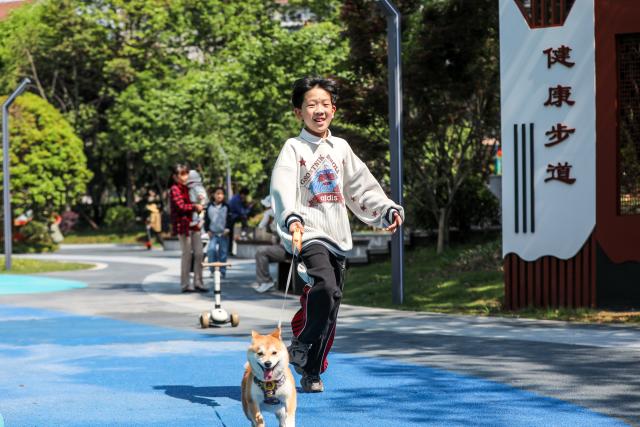 (260715) -- BEIJING, July 15, 2026 (Xinhua) -- A child walks a dog at a pocket park in Deqing County of Huzhou City, east China's Zhejiang Province, April 30, 2026. During China's 14th Five-Year Plan period (2021-2025), over 240,000 old urban residential compounds were renovated across the country, benefiting more than 40 million households and 110 million residents.
   Under urban renewal initiatives, 129,000 elevators have been installed, over 3.4 million parking spaces have been added, and 64,000 residential compound service facilities providing services such as senior and child care have been constructed.
   Entering the 15th Five-Year Plan period (2026-2030), China schedules to start the renovation work of another 115,000 old urban residential compounds, in an effort to inject new development vitality into old neighborhoods. (Photo by Bai Yu/Xinhua)