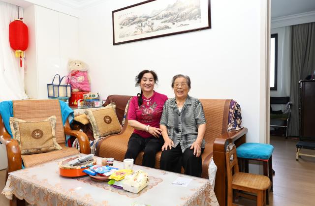 (260715) -- SHANGHAI, July 15, 2026 (Xinhua) -- Yu Meixiang (R) and her daughter Gan Landi are pictured at their new residence in Pengyi residential compound, Jing'an District, east China's Shanghai, July 14, 2026. In Shanghai's Pengpu Xincun, one of the city's earliest newly built residential areas for in-service staff, senior residents like 92-year-old Yu Meixiang and 75-year-old Peng Juhua shared their memories of bygone days at a gathering with children of the neighborhood. Their stories reflect not only personal history but also a remarkable urban renewal that has transformed their lives while keeping their community intact.
   Built mostly in the 1950s and 1960s, the residential buildings in Pengpu Xincun had long fallen into disrepair, as could be seen in the leaky roofs and crumbling walls. The daily hardships had been worsened by kitchens and bathrooms shared among neighbors, especially when families there were growing in sizes. 
   In response, the local government launched a renewal project in 2005. Residents temporarily relocated while their old homes were reconstructed on the original plots. After two decades of work in multiple phases, Pengyi residential compound of Pengpu Xincun officially opened for its earlier residents to move back in June 2025.
   The refurbished apartments there are now more spacious, each with a private kitchen and bathroom. Elevators, barrier-free access, and a pedestrian-friendly internal traffic system are now in place to make life much easier for the elderly. A neighborhood cultural center with a library and gym is set to open soon. (Xinhua/Fang Zhe)