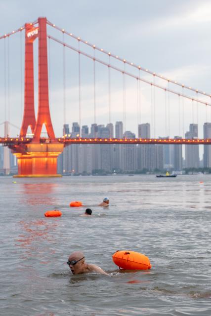 (260717) -- WUHAN, July 17, 2026 (Xinhua) -- A member of Yangtze River volunteer lifeguard team conducts river-crossing training at a park in Wuhan, central China's Hubei Province, July 10, 2026. Located at the confluence of the Yangtze River and its longest tributary, the Han River, Wuhan is home to 165 rivers and 166 lakes. These abundant water resources foster a deep-seated love for open-water swimming among Wuhan's inhabitants.
   This year marks the 51st edition of the Yangtze River crossing event. During the competition, swimmers from around the country and the world gather on the banks of the Yangtze River to race across the river. Yet behind every crossing, members of a volunteer team, the Yangtze River volunteer lifeguard team, always safeguard participants' safety with passion, courage and selfless dedication.
   Zhou Zhuan, 64, is a detachment captain of the Yangtze River volunteer lifeguard Team. This year marks his fourth time participating in rescue support work during the river crossing event. As a native of Wuhan who grew up by the river, Zhou has a deep affection for the Yangtze River. Having loved swimming for many years and wishing to contribute to the community, Zhou joined the team after retiring from work in 2017.
   On regular days, Zhou and team members conduct swimming training and riverbank patrols, carry out simulated rescues, and deliver safety awareness outreach program. During the summer flood season, members of the team take turns on duty along the riverbank to respond to emergencies. Established in 2010, the team now comprises over 3,500 members and has rescued more than 1,200 people to date. (Xinhua/Du Zixuan)