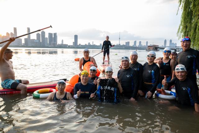 (260717) -- WUHAN, July 17, 2026 (Xinhua) -- Members of Yangtze River volunteer lifeguard team pose for a group photo at a park in Wuhan, central China's Hubei Province, July 10, 2026. Located at the confluence of the Yangtze River and its longest tributary, the Han River, Wuhan is home to 165 rivers and 166 lakes. These abundant water resources foster a deep-seated love for open-water swimming among Wuhan's inhabitants.
   This year marks the 51st edition of the Yangtze River crossing event. During the competition, swimmers from around the country and the world gather on the banks of the Yangtze River to race across the river. Yet behind every crossing, members of a volunteer team, the Yangtze River volunteer lifeguard team, always safeguard participants' safety with passion, courage and selfless dedication.
   Zhou Zhuan, 64, is a detachment captain of the Yangtze River volunteer lifeguard Team. This year marks his fourth time participating in rescue support work during the river crossing event. As a native of Wuhan who grew up by the river, Zhou has a deep affection for the Yangtze River. Having loved swimming for many years and wishing to contribute to the community, Zhou joined the team after retiring from work in 2017.
   On regular days, Zhou and team members conduct swimming training and riverbank patrols, carry out simulated rescues, and deliver safety awareness outreach program. During the summer flood season, members of the team take turns on duty along the riverbank to respond to emergencies. Established in 2010, the team now comprises over 3,500 members and has rescued more than 1,200 people to date. (Xinhua/Du Zixuan)