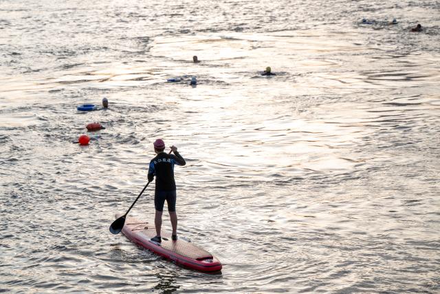 (260717) -- WUHAN, July 17, 2026 (Xinhua) -- Members of Yangtze River volunteer lifeguard team conduct river-crossing training at a park in Wuhan, central China's Hubei Province, July 10, 2026. Located at the confluence of the Yangtze River and its longest tributary, the Han River, Wuhan is home to 165 rivers and 166 lakes. These abundant water resources foster a deep-seated love for open-water swimming among Wuhan's inhabitants.
   This year marks the 51st edition of the Yangtze River crossing event. During the competition, swimmers from around the country and the world gather on the banks of the Yangtze River to race across the river. Yet behind every crossing, members of a volunteer team, the Yangtze River volunteer lifeguard team, always safeguard participants' safety with passion, courage and selfless dedication.
   Zhou Zhuan, 64, is a detachment captain of the Yangtze River volunteer lifeguard Team. This year marks his fourth time participating in rescue support work during the river crossing event. As a native of Wuhan who grew up by the river, Zhou has a deep affection for the Yangtze River. Having loved swimming for many years and wishing to contribute to the community, Zhou joined the team after retiring from work in 2017.
   On regular days, Zhou and team members conduct swimming training and riverbank patrols, carry out simulated rescues, and deliver safety awareness outreach program. During the summer flood season, members of the team take turns on duty along the riverbank to respond to emergencies. Established in 2010, the team now comprises over 3,500 members and has rescued more than 1,200 people to date. (Xinhua/Du Zixuan)