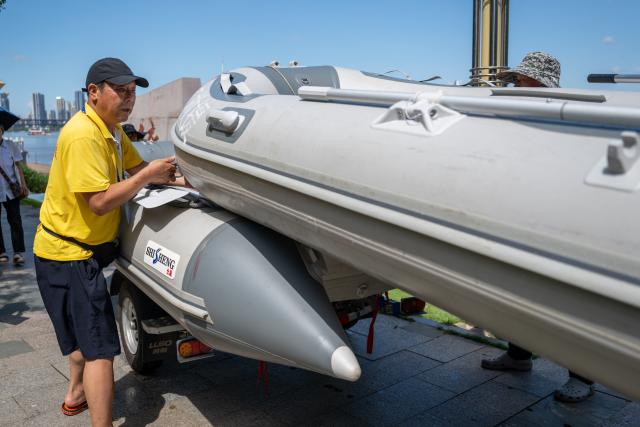 (260717) -- WUHAN, July 17, 2026 (Xinhua) -- Zhou Zhuan, with other members of Yangtze River volunteer lifeguard team, carries an inflatable boat ashore after a trial event before the 51st edition of the Yangtze River crossing event in Wuhan, central China's Hubei Province, July 9, 2026. Located at the confluence of the Yangtze River and its longest tributary, the Han River, Wuhan is home to 165 rivers and 166 lakes. These abundant water resources foster a deep-seated love for open-water swimming among Wuhan's inhabitants.
   This year marks the 51st edition of the Yangtze River crossing event. During the competition, swimmers from around the country and the world gather on the banks of the Yangtze River to race across the river. Yet behind every crossing, members of a volunteer team, the Yangtze River volunteer lifeguard team, always safeguard participants' safety with passion, courage and selfless dedication.
   Zhou Zhuan, 64, is a detachment captain of the Yangtze River volunteer lifeguard Team. This year marks his fourth time participating in rescue support work during the river crossing event. As a native of Wuhan who grew up by the river, Zhou has a deep affection for the Yangtze River. Having loved swimming for many years and wishing to contribute to the community, Zhou joined the team after retiring from work in 2017.
   On regular days, Zhou and team members conduct swimming training and riverbank patrols, carry out simulated rescues, and deliver safety awareness outreach program. During the summer flood season, members of the team take turns on duty along the riverbank to respond to emergencies. Established in 2010, the team now comprises over 3,500 members and has rescued more than 1,200 people to date. (Xinhua/Du Zixuan)