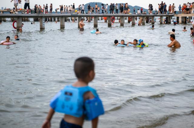 (260717) -- WUHAN, July 17, 2026 (Xinhua) -- People enjoy their leisure time at the water area near Wuhan University in Wuhan, central China's Hubei Province, July 15, 2026. Located at the confluence of the Yangtze River and its longest tributary, the Han River, Wuhan is home to 165 rivers and 166 lakes. These abundant water resources foster a deep-seated love for open-water swimming among Wuhan's inhabitants.
   This year marks the 51st edition of the Yangtze River crossing event. During the competition, swimmers from around the country and the world gather on the banks of the Yangtze River to race across the river. Yet behind every crossing, members of a volunteer team, the Yangtze River volunteer lifeguard team, always safeguard participants' safety with passion, courage and selfless dedication.
   Zhou Zhuan, 64, is a detachment captain of the Yangtze River volunteer lifeguard Team. This year marks his fourth time participating in rescue support work during the river crossing event. As a native of Wuhan who grew up by the river, Zhou has a deep affection for the Yangtze River. Having loved swimming for many years and wishing to contribute to the community, Zhou joined the team after retiring from work in 2017.
   On regular days, Zhou and team members conduct swimming training and riverbank patrols, carry out simulated rescues, and deliver safety awareness outreach program. During the summer flood season, members of the team take turns on duty along the riverbank to respond to emergencies. Established in 2010, the team now comprises over 3,500 members and has rescued more than 1,200 people to date. (Xinhua/Du Zixuan)