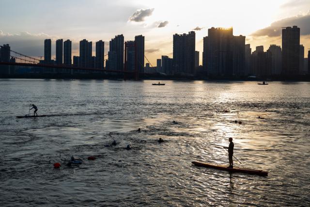 (260717) -- WUHAN, July 17, 2026 (Xinhua) -- Members of Yangtze River volunteer lifeguard team conduct river-crossing training at a park in Wuhan, central China's Hubei Province, July 10, 2026. Located at the confluence of the Yangtze River and its longest tributary, the Han River, Wuhan is home to 165 rivers and 166 lakes. These abundant water resources foster a deep-seated love for open-water swimming among Wuhan's inhabitants.
   This year marks the 51st edition of the Yangtze River crossing event. During the competition, swimmers from around the country and the world gather on the banks of the Yangtze River to race across the river. Yet behind every crossing, members of a volunteer team, the Yangtze River volunteer lifeguard team, always safeguard participants' safety with passion, courage and selfless dedication.
   Zhou Zhuan, 64, is a detachment captain of the Yangtze River volunteer lifeguard Team. This year marks his fourth time participating in rescue support work during the river crossing event. As a native of Wuhan who grew up by the river, Zhou has a deep affection for the Yangtze River. Having loved swimming for many years and wishing to contribute to the community, Zhou joined the team after retiring from work in 2017.
   On regular days, Zhou and team members conduct swimming training and riverbank patrols, carry out simulated rescues, and deliver safety awareness outreach program. During the summer flood season, members of the team take turns on duty along the riverbank to respond to emergencies. Established in 2010, the team now comprises over 3,500 members and has rescued more than 1,200 people to date. (Xinhua/Du Zixuan)
