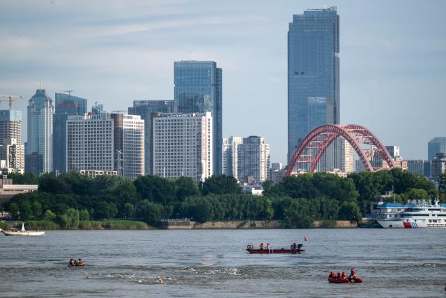 (260717) -- WUHAN, July 17, 2026 (Xinhua) -- Participants compete during the 51st edition of the Yangtze River crossing event in Wuhan, central China's Hubei Province, July 16, 2026. Located at the confluence of the Yangtze River and its longest tributary, the Han River, Wuhan is home to 165 rivers and 166 lakes. These abundant water resources foster a deep-seated love for open-water swimming among Wuhan's inhabitants.
   This year marks the 51st edition of the Yangtze River crossing event. During the competition, swimmers from around the country and the world gather on the banks of the Yangtze River to race across the river. Yet behind every crossing, members of a volunteer team, the Yangtze River volunteer lifeguard team, always safeguard participants' safety with passion, courage and selfless dedication.
   Zhou Zhuan, 64, is a detachment captain of the Yangtze River volunteer lifeguard Team. This year marks his fourth time participating in rescue support work during the river crossing event. As a native of Wuhan who grew up by the river, Zhou has a deep affection for the Yangtze River. Having loved swimming for many years and wishing to contribute to the community, Zhou joined the team after retiring from work in 2017.
   On regular days, Zhou and team members conduct swimming training and riverbank patrols, carry out simulated rescues, and deliver safety awareness outreach program. During the summer flood season, members of the team take turns on duty along the riverbank to respond to emergencies. Established in 2010, the team now comprises over 3,500 members and has rescued more than 1,200 people to date. (Xinhua/Du Zixuan)