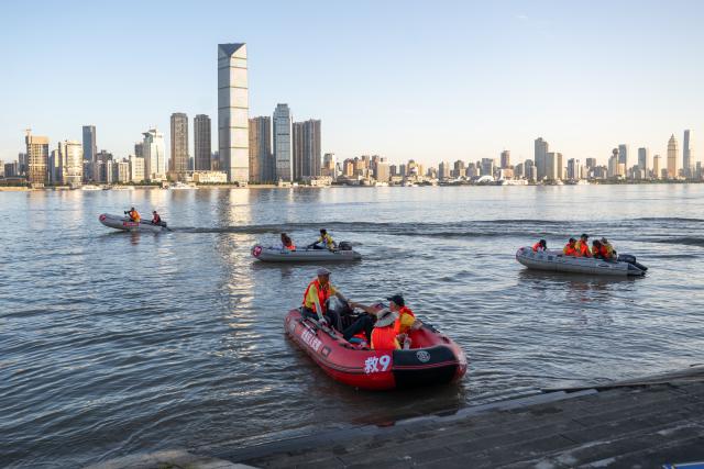 (260717) -- WUHAN, July 17, 2026 (Xinhua) -- Members of Yangtze River volunteer lifeguard team take inflatable boats to participate in a trial event before the 51st edition of the Yangtze River crossing event in Wuhan, central China's Hubei Province, July 9, 2026. Located at the confluence of the Yangtze River and its longest tributary, the Han River, Wuhan is home to 165 rivers and 166 lakes. These abundant water resources foster a deep-seated love for open-water swimming among Wuhan's inhabitants.
   This year marks the 51st edition of the Yangtze River crossing event. During the competition, swimmers from around the country and the world gather on the banks of the Yangtze River to race across the river. Yet behind every crossing, members of a volunteer team, the Yangtze River volunteer lifeguard team, always safeguard participants' safety with passion, courage and selfless dedication.
   Zhou Zhuan, 64, is a detachment captain of the Yangtze River volunteer lifeguard Team. This year marks his fourth time participating in rescue support work during the river crossing event. As a native of Wuhan who grew up by the river, Zhou has a deep affection for the Yangtze River. Having loved swimming for many years and wishing to contribute to the community, Zhou joined the team after retiring from work in 2017.
   On regular days, Zhou and team members conduct swimming training and riverbank patrols, carry out simulated rescues, and deliver safety awareness outreach program. During the summer flood season, members of the team take turns on duty along the riverbank to respond to emergencies. Established in 2010, the team now comprises over 3,500 members and has rescued more than 1,200 people to date. (Xinhua/Du Zixuan)