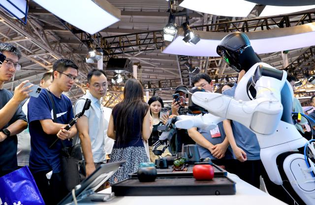 (260718) -- SHANGHAI, July 18, 2026 (Xinhua) -- Visitors watch a robot performing traditional tea art during the 2026 World AI Conference and High-Level Meeting on Global AI Governance in Shanghai, east China, July 18, 2026. The event scheduled from Friday to Monday showcases exhibitions of smart devices, AI plus culture and entertainment experiences, and a wide range of cutting-edge AI products, among which a range of humanoid robots and AI-powered dexterous hands as one of the highlights. 
During the event, a variety of intelligent robots adaptable to diverse scenarios for industrial production and daily life are displayed. Notably, the country's annual output of humanoid robots is projected to exceed 100,000 units this year. (Xinhua/Fang Zhe)