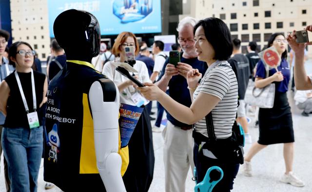(260718) -- SHANGHAI, July 18, 2026 (Xinhua) -- A "robot volunteer" receives an interview during the 2026 World AI Conference and High-Level Meeting on Global AI Governance in Shanghai, east China, July 18, 2026. The event scheduled from Friday to Monday showcases exhibitions of smart devices, AI plus culture and entertainment experiences, and a wide range of cutting-edge AI products, among which a range of humanoid robots and AI-powered dexterous hands as one of the highlights. 
During the event, a variety of intelligent robots adaptable to diverse scenarios for industrial production and daily life are displayed. Notably, the country's annual output of humanoid robots is projected to exceed 100,000 units this year. (Xinhua/Fang Zhe)