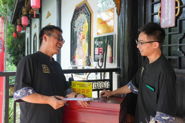 (260718) -- CHENGDU, July 18, 2026 (Xinhua) -- Yuan Xilin (L) and his colleague Xu Bin talk before the opening of a Sichuan Opera theater for guests in Chengdu, southwest China's Sichuan Province, July 15, 2026. At 34, Yuan Xilin works as a ticket attendant at a Sichuan Opera theater in Chengdu, where he checks tickets, welcomes visitors and helps audiences find their way into the theater.
As Chengdu attracts growing numbers of international visitors interested in traditional Chinese opera and Sichuan Opera, Yuan meets dozens of overseas tourists every day. Hoping to make them feel more at ease, he began learning simple greetings in different languages so he could welcome them in their native tongue.
Yuan's interest in languages began in high school, when he came across a booklet introducing several foreign languages. Drawn to the rhythm of Spanish music and the sound of classical guitar, he developed a particular interest in Spanish.
As China's visa-free transit and other travel facilitation policies have brought more international visitors to the country, Yuan has expanded his language skills from English and Spanish to Italian, French, Portuguese, Russian, Polish and more. What once began with a simple greeting has gradually grown into brief conversations about visitors' experiences in China and introductions to Chengdu's local culture.
For Yuan, language is a bridge between cultures. He believes that even a simple greeting in a visitor's native language can make them feel welcome while creating opportunities for cultural exchange and his own personal growth. (Xinhua/Wang Xi)