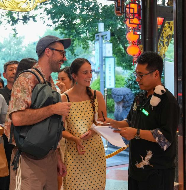 (260718) -- CHENGDU, July 18, 2026 (Xinhua) -- Yuan Xilin (1st R) checks tickets and guides tourists from Italy into the Sichuan Opera theater in Chengdu, southwest China's Sichuan Province, July 8, 2026. At 34, Yuan Xilin works as a ticket attendant at a Sichuan Opera theater in Chengdu, where he checks tickets, welcomes visitors and helps audiences find their way into the theater.
As Chengdu attracts growing numbers of international visitors interested in traditional Chinese opera and Sichuan Opera, Yuan meets dozens of overseas tourists every day. Hoping to make them feel more at ease, he began learning simple greetings in different languages so he could welcome them in their native tongue.
Yuan's interest in languages began in high school, when he came across a booklet introducing several foreign languages. Drawn to the rhythm of Spanish music and the sound of classical guitar, he developed a particular interest in Spanish.
As China's visa-free transit and other travel facilitation policies have brought more international visitors to the country, Yuan has expanded his language skills from English and Spanish to Italian, French, Portuguese, Russian, Polish and more. What once began with a simple greeting has gradually grown into brief conversations about visitors' experiences in China and introductions to Chengdu's local culture.
For Yuan, language is a bridge between cultures. He believes that even a simple greeting in a visitor's native language can make them feel welcome while creating opportunities for cultural exchange and his own personal growth. (Xinhua/Wang Xi)
