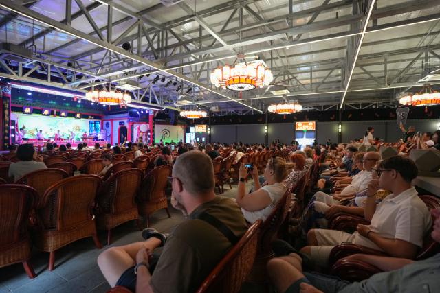 (260718) -- CHENGDU, July 18, 2026 (Xinhua) -- Foreign tourists watch a performance at a Sichuan opera theater in Chengdu, southwest China's Sichuan Province, July 8, 2026. At 34, Yuan Xilin works as a ticket attendant at a Sichuan Opera theater in Chengdu, where he checks tickets, welcomes visitors and helps audiences find their way into the theater.
As Chengdu attracts growing numbers of international visitors interested in traditional Chinese opera and Sichuan Opera, Yuan meets dozens of overseas tourists every day. Hoping to make them feel more at ease, he began learning simple greetings in different languages so he could welcome them in their native tongue.
Yuan's interest in languages began in high school, when he came across a booklet introducing several foreign languages. Drawn to the rhythm of Spanish music and the sound of classical guitar, he developed a particular interest in Spanish.
As China's visa-free transit and other travel facilitation policies have brought more international visitors to the country, Yuan has expanded his language skills from English and Spanish to Italian, French, Portuguese, Russian, Polish and more. What once began with a simple greeting has gradually grown into brief conversations about visitors' experiences in China and introductions to Chengdu's local culture.
For Yuan, language is a bridge between cultures. He believes that even a simple greeting in a visitor's native language can make them feel welcome while creating opportunities for cultural exchange and his own personal growth. (Xinhua/Wang Xi)