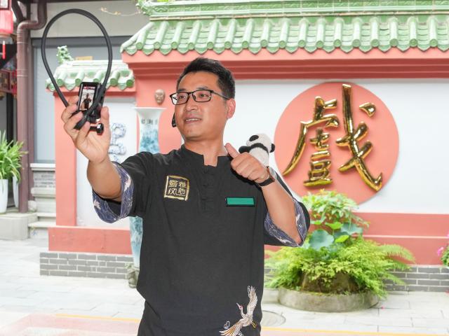 (260718) -- CHENGDU, July 18, 2026 (Xinhua) -- Yuan Xilin records a short video introduction before the Sichuan Opera theater opens to guests in Chengdu, southwest China's Sichuan Province, July 8, 2026. At 34, Yuan Xilin works as a ticket attendant at a Sichuan Opera theater in Chengdu, where he checks tickets, welcomes visitors and helps audiences find their way into the theater.
As Chengdu attracts growing numbers of international visitors interested in traditional Chinese opera and Sichuan Opera, Yuan meets dozens of overseas tourists every day. Hoping to make them feel more at ease, he began learning simple greetings in different languages so he could welcome them in their native tongue.
Yuan's interest in languages began in high school, when he came across a booklet introducing several foreign languages. Drawn to the rhythm of Spanish music and the sound of classical guitar, he developed a particular interest in Spanish.
As China's visa-free transit and other travel facilitation policies have brought more international visitors to the country, Yuan has expanded his language skills from English and Spanish to Italian, French, Portuguese, Russian, Polish and more. What once began with a simple greeting has gradually grown into brief conversations about visitors' experiences in China and introductions to Chengdu's local culture.
For Yuan, language is a bridge between cultures. He believes that even a simple greeting in a visitor's native language can make them feel welcome while creating opportunities for cultural exchange and his own personal growth. (Xinhua/Wang Xi)