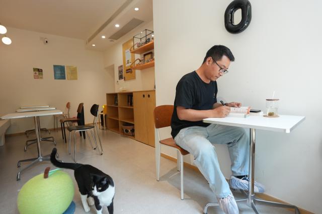 (260718) -- CHENGDU, July 18, 2026 (Xinhua) -- Yuan Xilin studies Spanish in a café in Chengdu, southwest China's Sichuan Province, July 15, 2026. At 34, Yuan Xilin works as a ticket attendant at a Sichuan Opera theater in Chengdu, where he checks tickets, welcomes visitors and helps audiences find their way into the theater.
As Chengdu attracts growing numbers of international visitors interested in traditional Chinese opera and Sichuan Opera, Yuan meets dozens of overseas tourists every day. Hoping to make them feel more at ease, he began learning simple greetings in different languages so he could welcome them in their native tongue.
Yuan's interest in languages began in high school, when he came across a booklet introducing several foreign languages. Drawn to the rhythm of Spanish music and the sound of classical guitar, he developed a particular interest in Spanish.
As China's visa-free transit and other travel facilitation policies have brought more international visitors to the country, Yuan has expanded his language skills from English and Spanish to Italian, French, Portuguese, Russian, Polish and more. What once began with a simple greeting has gradually grown into brief conversations about visitors' experiences in China and introductions to Chengdu's local culture.
For Yuan, language is a bridge between cultures. He believes that even a simple greeting in a visitor's native language can make them feel welcome while creating opportunities for cultural exchange and his own personal growth. (Xinhua/Wang Xi)