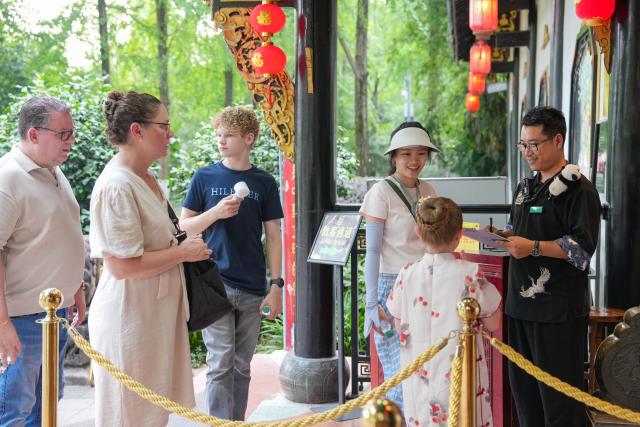 (260718) -- CHENGDU, July 18, 2026 (Xinhua) -- Yuan Xilin (1st R) talks with Dutch tourists at a Sichuan opera theater in Chengdu, southwest China's Sichuan Province, July 8, 2026. At 34, Yuan Xilin works as a ticket attendant at a Sichuan Opera theater in Chengdu, where he checks tickets, welcomes visitors and helps audiences find their way into the theater.
As Chengdu attracts growing numbers of international visitors interested in traditional Chinese opera and Sichuan Opera, Yuan meets dozens of overseas tourists every day. Hoping to make them feel more at ease, he began learning simple greetings in different languages so he could welcome them in their native tongue.
Yuan's interest in languages began in high school, when he came across a booklet introducing several foreign languages. Drawn to the rhythm of Spanish music and the sound of classical guitar, he developed a particular interest in Spanish.
As China's visa-free transit and other travel facilitation policies have brought more international visitors to the country, Yuan has expanded his language skills from English and Spanish to Italian, French, Portuguese, Russian, Polish and more. What once began with a simple greeting has gradually grown into brief conversations about visitors' experiences in China and introductions to Chengdu's local culture.
For Yuan, language is a bridge between cultures. He believes that even a simple greeting in a visitor's native language can make them feel welcome while creating opportunities for cultural exchange and his own personal growth. (Xinhua/Wang Xi)