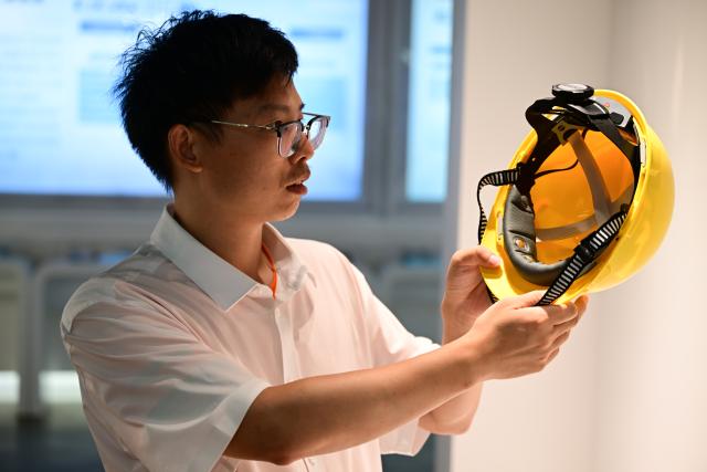 (260718) -- BENGBU, July 18, 2026 (Xinhua) -- A staff member displays a brain-computer interface (BCI) helmet at an exhibition hall of Anhui North Microelectronics Research Institute Group Co., Ltd. in Bengbu, east China's Anhui Province, July 17, 2026. Bengbu, a traditional industrial city, has stepped up the development of its brain-computer interface (BCI) industry in recent years. By strengthening collaboration among industry, research institutes and medical institutions, Bengbu has built an innovation ecosystem that supports both BCI research and clinical application, aiming to become an emerging BCI innovation hub in the Yangtze River Delta region. (Xinhua/Zhou Mu)