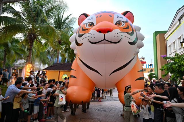 (260718) -- HAIKOU, July 18, 2026 (Xinhua) -- Performers interact with audiences during a carnival parade in Haikou, south China's Hainan Province, July 18, 2026. The 2026 Hainan Island Carnival opened here on Saturday and will last until Aug. 18, during which over 50 special events will be held. (Xinhua/Guo Cheng)