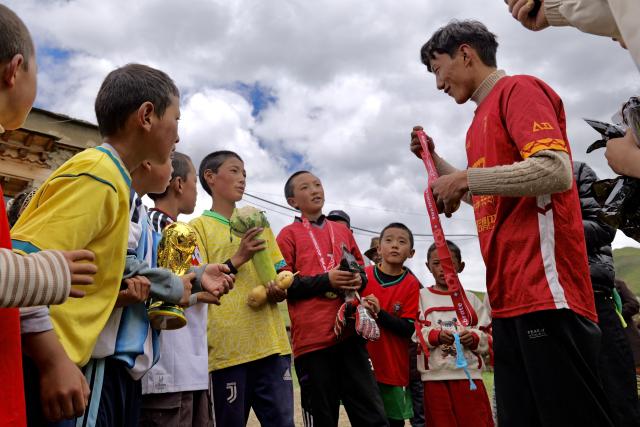 (260719) -- LHASA, July 19, 2026 (Xinhua) -- Sonam Jigme (1st R) presents the champion team members with a model of the World Cup trophy, a homemade vegetable cup and medals after a match in Zangbi Township of Lhari County, Nagqu, southwest China's Xizang Autonomous Region, July 18, 2026.
  TO GO WITH "Letter from Lhasa: Football dreams at an altitude of 4,700 meters" (Xinhua/Zhou Yulong)