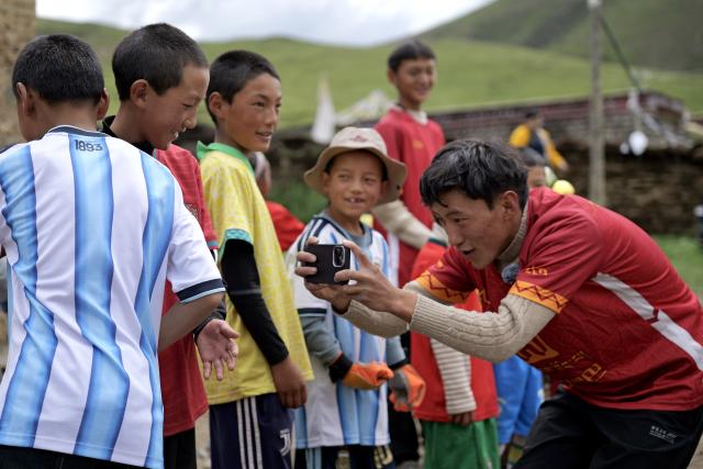 (260719) -- LHASA, July 19, 2026 (Xinhua) -- Sonam Jigme (1st R) takes videos for players in Zangbi Township of Lhari County, Nagqu, southwest China's Xizang Autonomous Region, July 18, 2026.
  TO GO WITH "Letter from Lhasa: Football dreams at an altitude of 4,700 meters" (Xinhua/Zhou Yulong)