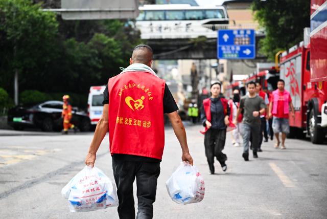(260719) -- CHONGQING, July 19, 2026 (Xinhua) -- A volunteer carries supplies near the rescue site of a mountain collapse in Pengshui Miao and Tujia Autonomous County of Chongqing, southwest China, July 19, 2026. A rainfall-induced mountain collapse occurred at 9:08 a.m. on Friday in the Hanjia sub-district of Pengshui, burying more than 10 residential buildings, while leaving some local residents trapped and unaccounted for. 
  China activated a Level-II national emergency response for geological disasters. Multiple rescue forces including emergency response, fire control and public security rushed to the scene and launched full-scale search and rescue operations, while local residents also volunteered to take part in the rescue efforts. (Xinhua/Wang Quanchao)