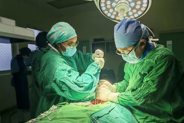 (260719) -- MBEYA, July 19, 2026 (Xinhua) -- This photo taken with a mobile phone shows Chinese spine surgeon Zhou Chao (R) and a local doctor performing a surgery for a Tanzanian patient at Mbeya Zonal Referral Hospital in Mbeya, Tanzania, June 15, 2026. TO GO WITH "Feature: Chinese doctors bring hope to Tanzanian mother after pioneering spine surgery" (The 28th Chinese medical team in Tanzania/Handout via Xinhua)