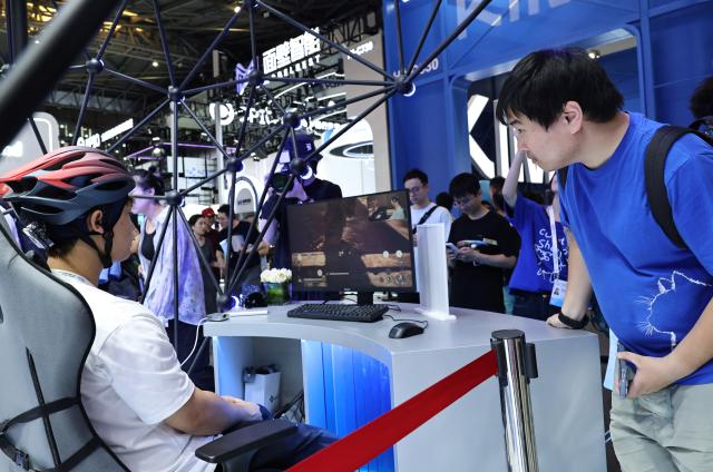 (260719) -- SHANGHAI, July 19, 2026 (Xinhua) -- A visitor watches a staff member operating a computer game via a non-invasive electroencephalogram device during the 2026 World AI Conference and High-Level Meeting on Global AI Governance in Shanghai, east China, July 19, 2026. The event scheduled from Friday to Monday showcases exhibitions of a number of AI agent hardware and system products, highlighting the transition of next-generation AI from a tool to an intelligent partner, empowering various industries and everyday life. (Xinhua/Fang Zhe)