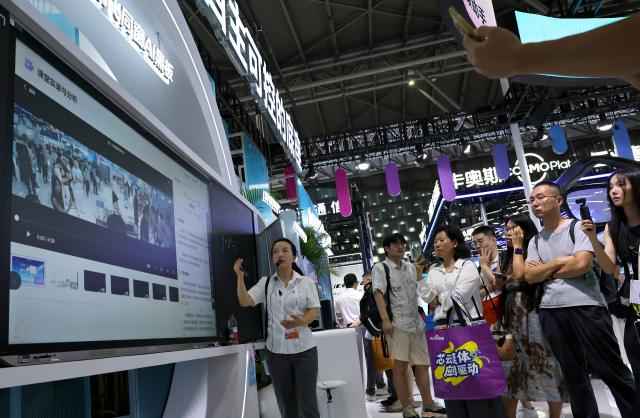 (260719) -- SHANGHAI, July 19, 2026 (Xinhua) -- A staff member (L) introduces functions of the iFlytek AI blackboard during the 2026 World AI Conference and High-Level Meeting on Global AI Governance in Shanghai, east China, July 19, 2026. The event scheduled from Friday to Monday showcases exhibitions of a number of AI agent hardware and system products, highlighting the transition of next-generation AI from a tool to an intelligent partner, empowering various industries and everyday life. (Xinhua/Fang Zhe)
