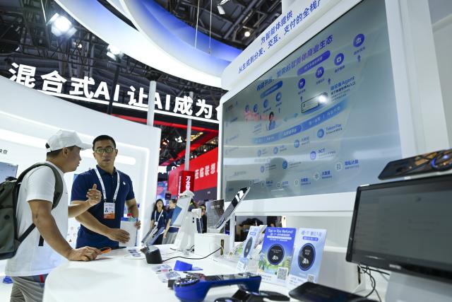 (260719) -- SHANGHAI, July 19, 2026 (Xinhua) -- A staff member (R) introduces the agent business ecosystem to a visitor at the booth of Ant Group during the 2026 World AI Conference and High-Level Meeting on Global AI Governance in Shanghai, east China, July 19, 2026. The event scheduled from Friday to Monday showcases exhibitions of a number of AI agent hardware and system products, highlighting the transition of next-generation AI from a tool to an intelligent partner, empowering various industries and everyday life. (Xinhua/Chen Haoming)